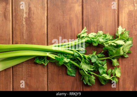 An overhead photo of fresh organic celery stalks with leaves on a dark rustic wooden background with a place for text Stock Photo