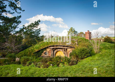 Hobbiton movie, Matamata, New Zealand. Quaint little Hobbit house with yellow door, in a green, sunny hillside landscape