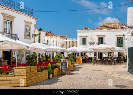 Tourists rest in streets cafe on a pedestrian area in old town. Faro, Algarve, Portugal Stock Photo