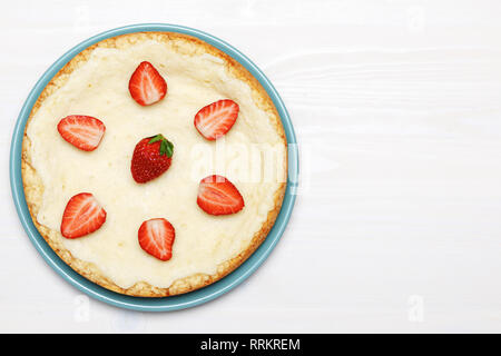 A whole classic cheesecake with strawberries on a white background. Top view.