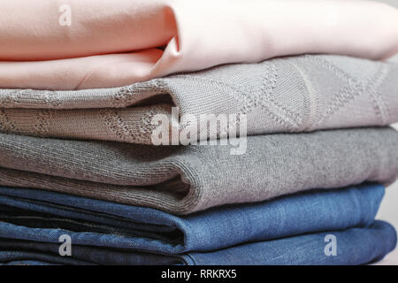A stack of folded clothes in blue , pink and gray color. Close-up. Stock Photo