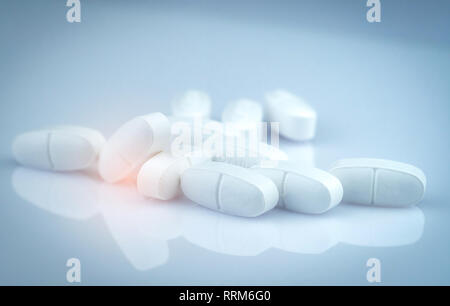 Pile of white oblong tablets pills on gradient background. Pharmaceutical industry. Pharmacy product. Global healthcare. Drug in pharmacy drugstore Stock Photo