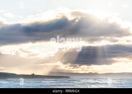 Sun light streams through parting clouds over the California coastline near Cambria, San Simeon, and Big Sur.  Creating a stunning view from a vista. Stock Photo