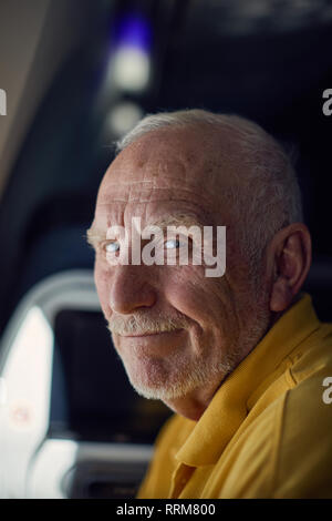 Friendly senior male smiling while traveling on airplane Stock Photo