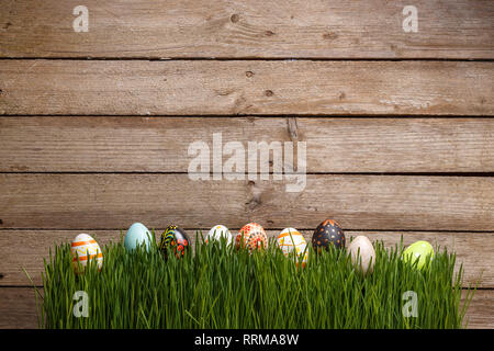 Decorated Easter eggs in the grass on wooden background, copy space Stock Photo