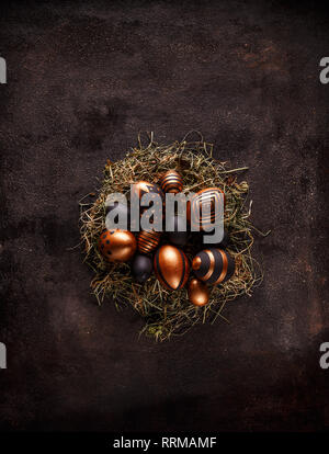 Background with golden decorated Easter eggs in nest on black background Stock Photo