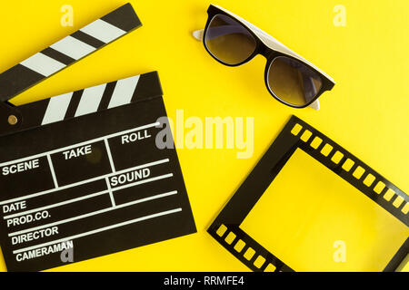 Cinema and movie making background. Clapperboard with 3d glasses and frame in form of film strip isolated on yellow background minimal creative concep Stock Photo