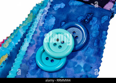 Multi-colored remnants of fabric  with large colorful buttons laying on top isolated on white Stock Photo