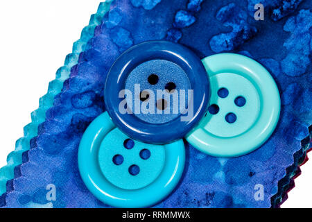 Multi-colored remnants of fabric  with large colorful buttons laying on top isolated on white Stock Photo