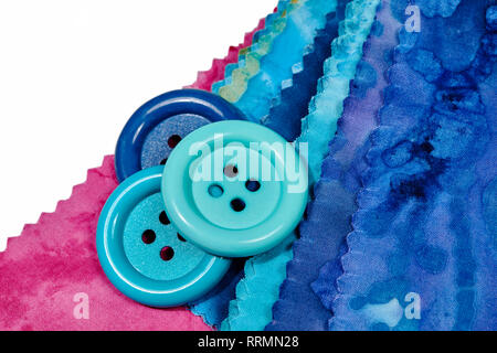 Multi-colored remnants of fabric  with large buttons laying on top isolated on white Stock Photo