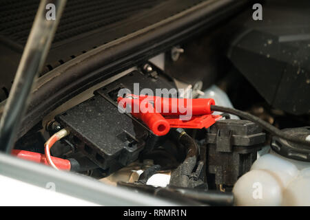 Jumper cable attached under car hood to help start car engine. Car repairs workshop Stock Photo