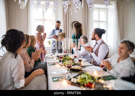 A young couple giving a gift to an old mother on a family birthday party. Stock Photo
