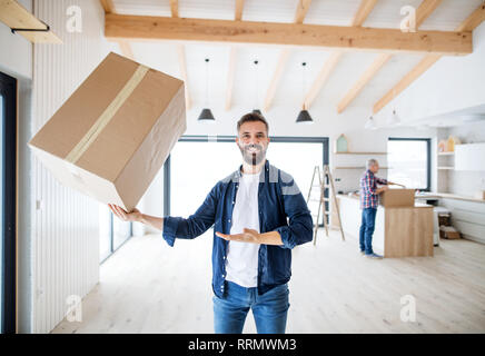 A mature man holding a large box in one hand when furnishing new house, a new home concept. Stock Photo