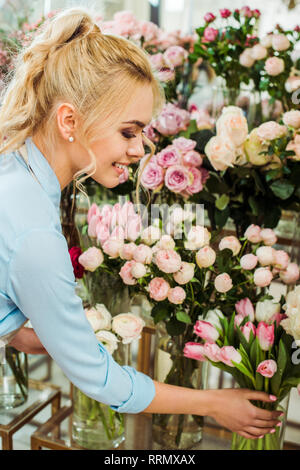 beautiful smiling woman choosing flowers in flower shop Stock Photo