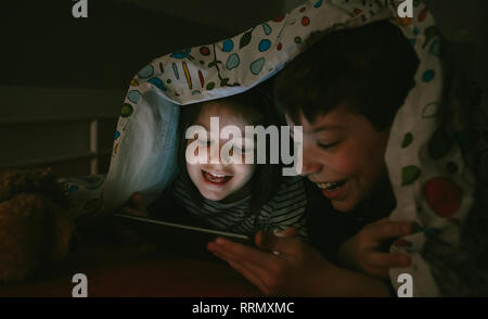 Brothers looking at the tablet in the dark Stock Photo