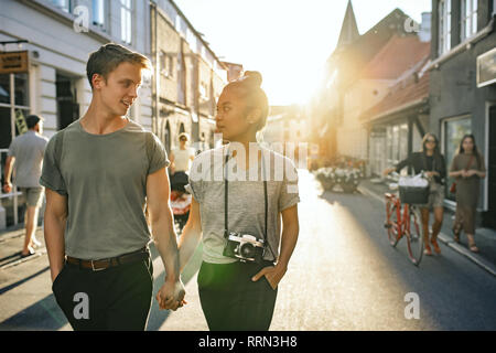 Young couple smiling while exploring the city together on foot Stock Photo