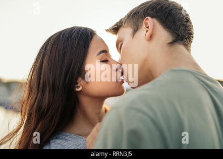 Romantic young couple kissing each other outside in the afternoon Stock Photo