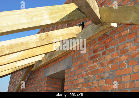 Close up on installation of wooden beams at construction the roof truss system of the house. Roofing Construction. Building Attic Interior. Stock Photo