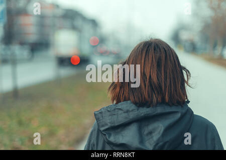 Rear view of woman on city street in cold winter afternoon Stock Photo