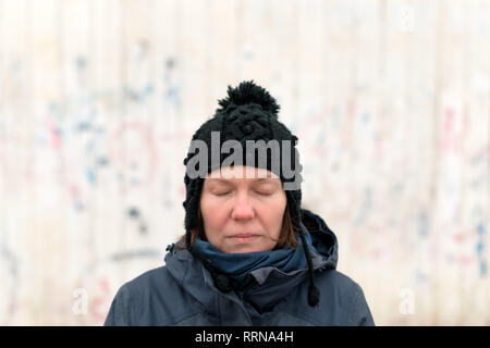 Portrait of serious woman with eyes closed on the street on cold winter day Stock Photo