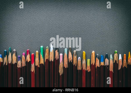 Row of artist pastel pencils on gray pastel paper sheet. Stock Photo