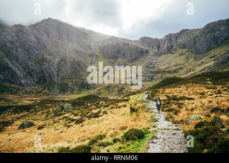 Woman walking along craggy mountain trail, Snowdonia NP, UK Stock Photo