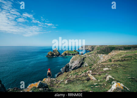 Woman standing on sunny cliffs with ocean view, Cornwall, UK Stock Photo
