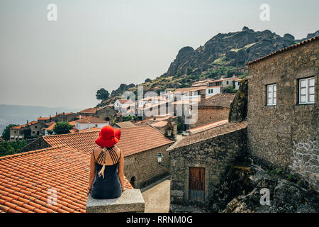 Woman in red hat looking at buildings on hillside, Monsanto, Portugal Stock Photo