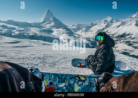 Personal perspective snowboarders on snowy ski slope, Zermatt, Switzerland Stock Photo