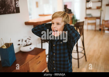 Playful, silly boy sticking out tongue and covering ears Stock Photo