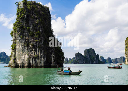 Traditional Vietnamese fishing boats sail between limestone rock islands in Ha Long Bay in South China Sea. Quảng Ninh, Vietnam, southeast Asia Stock Photo