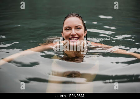 Portrait smiling young woman swimming in lake Stock Photo