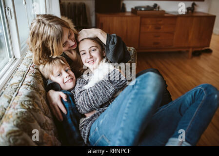 Portrait affectionate mother and children with guinea pig on living room sofa Stock Photo