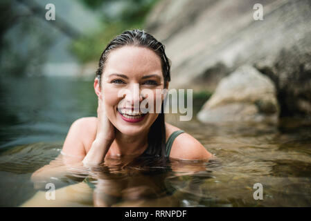 Portrait smiling, beautiful young woman swimming in lake Stock Photo