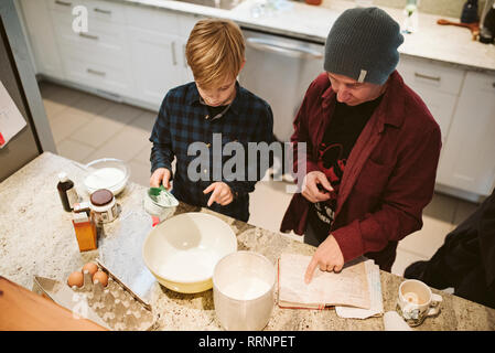 Father and son baking, looking at recipe in kitchen Stock Photo