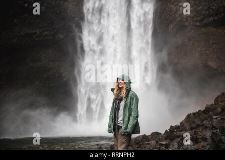 Smiling female hiker in rain jacket at waterfall, Whistler, British Columbia, Canada Stock Photo