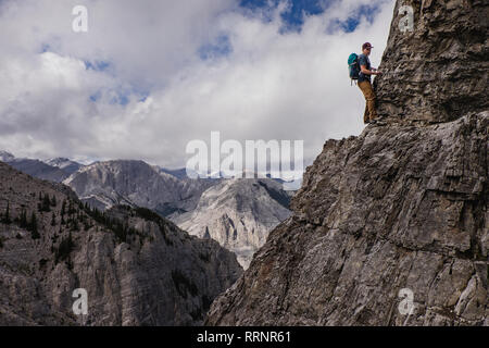 Man mountain climbing steep, craggy mountain face Stock Photo