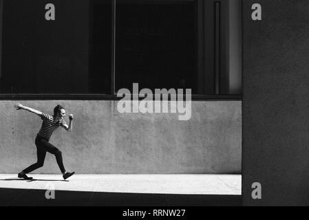 Young man walking on sunny urban sidewalk Stock Photo