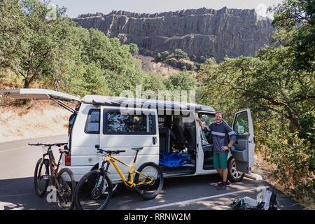 Portrait confident man with mountain bikes at van in remote parking lot, Hood River, Oregon, USA Stock Photo