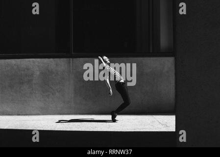 Young man dancing on urban sidewalk Stock Photo