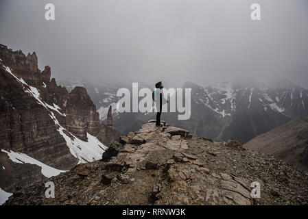 Female hiker on top of craggy, foggy mountain Banff, Alberta, Canada Stock Photo