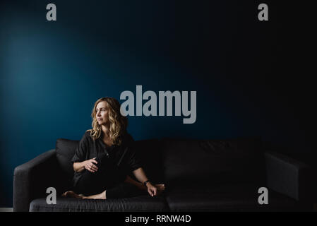 Serene, thoughtful woman on sofa looking away Stock Photo