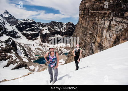 Female hikers hiking snowy mountain slope, Yoho Park, British Columbia, Canada Stock Photo