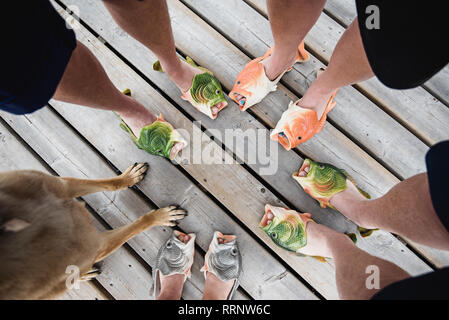 View from above friends wearing humorous fish slippers on dock Stock Photo