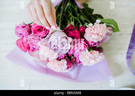 cropped view of female florist arranging bouquet with pink roses and carnations Stock Photo