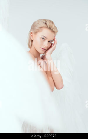 selective focus of beautiful woman with angel wings looking at camera isolated on white Stock Photo