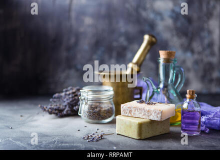 Bouquet of dry lavender,, a copper mortar with a pestle, pieces of homemade soap and oil for massage in glass bottles. Set of lavender spa products on Stock Photo