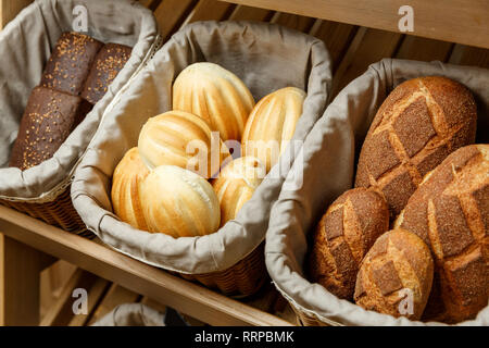 Assortment of fresh bread in baskets on the shelves in bakery Stock Photo