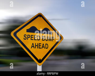 Speed Bump Sign - Yellow Road Traffic Warning Sign, on a Speeding Blurred Background Stock Photo