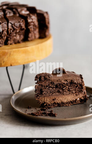 Prague chocolate cake on gray plate. Cake on wooden stand. Vertical, close up Stock Photo